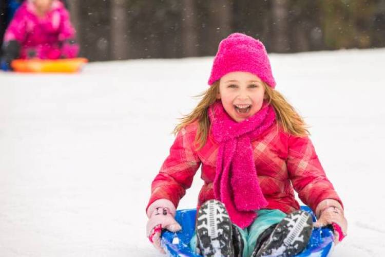 Girl in a pink coat sledding