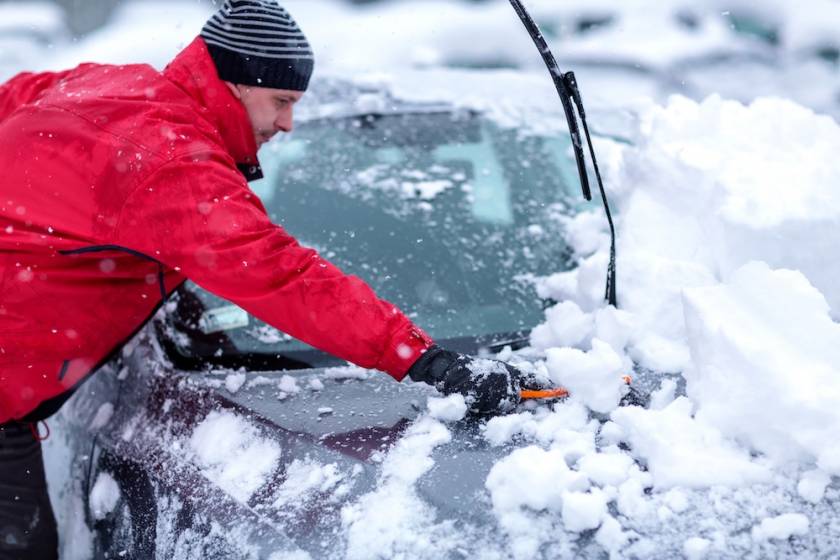 person getting snow off their car